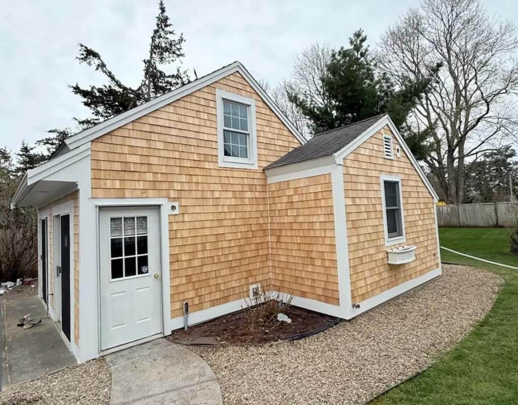 Freshly installed natural cedar shake siding on a home addition with clean white trim boards by Imagine Construction.