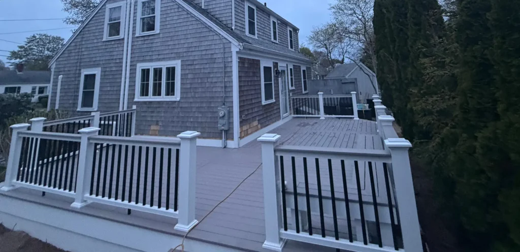 Sprawling gray composite deck wrapping around a multi-story gray cedar shake residential home by Imagine Construction.