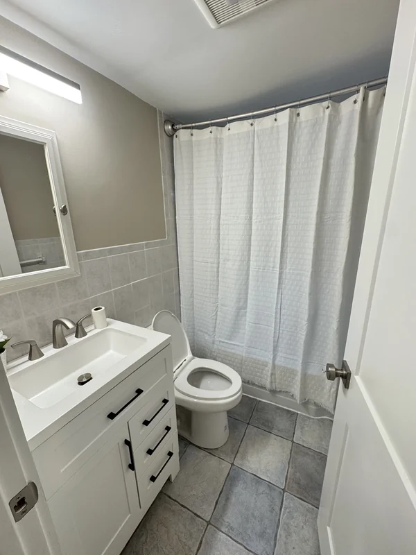 Finished bathroom with white vanity, shower, and neutral walls