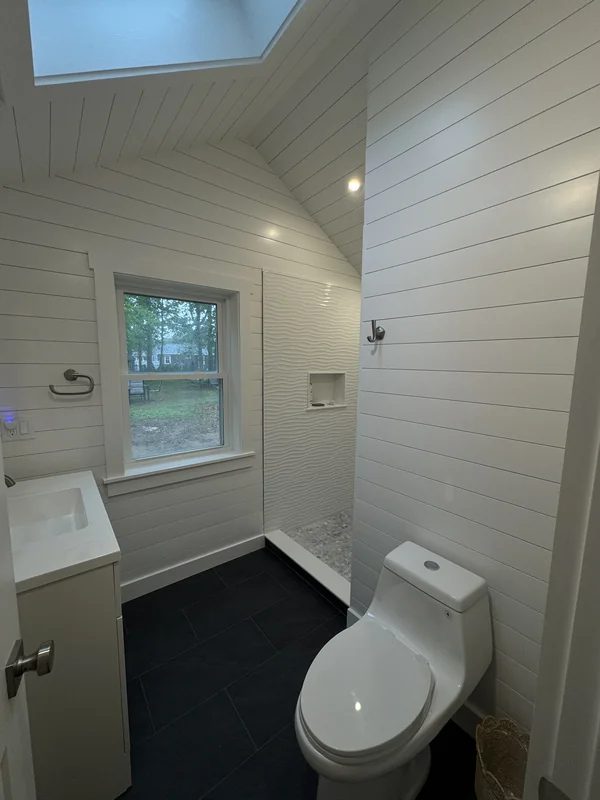 Bright bathroom with skylight, white wall paneling, and dark floor