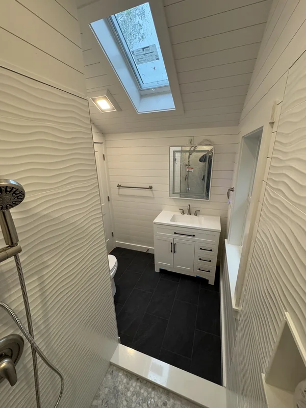 Narrow finished bathroom with skylight, vanity, and black flooring