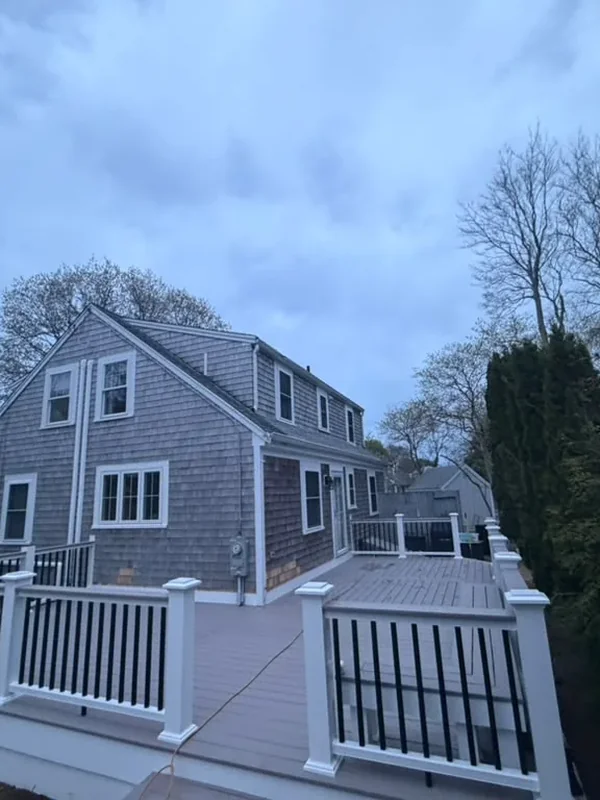 Large composite deck with white railings behind a gray home