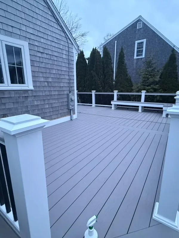 Composite deck attached to the rear of a gray shingle home