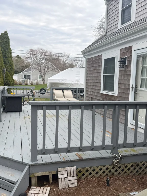 Gray deck with darker railing and steps beside the house