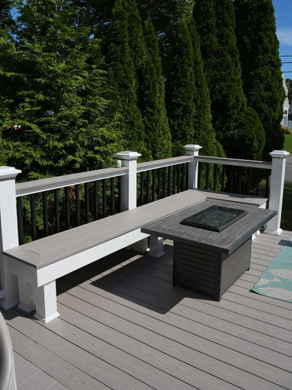Composite deck seating area with fire pit and white railing