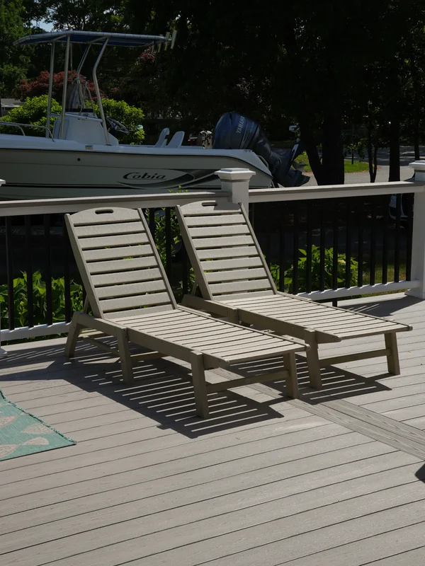 Composite deck stairs with white trim beside a home