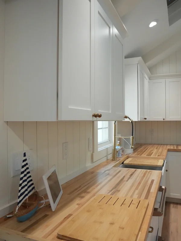 Kitchen counter and backsplash with white cabinets and wood surface