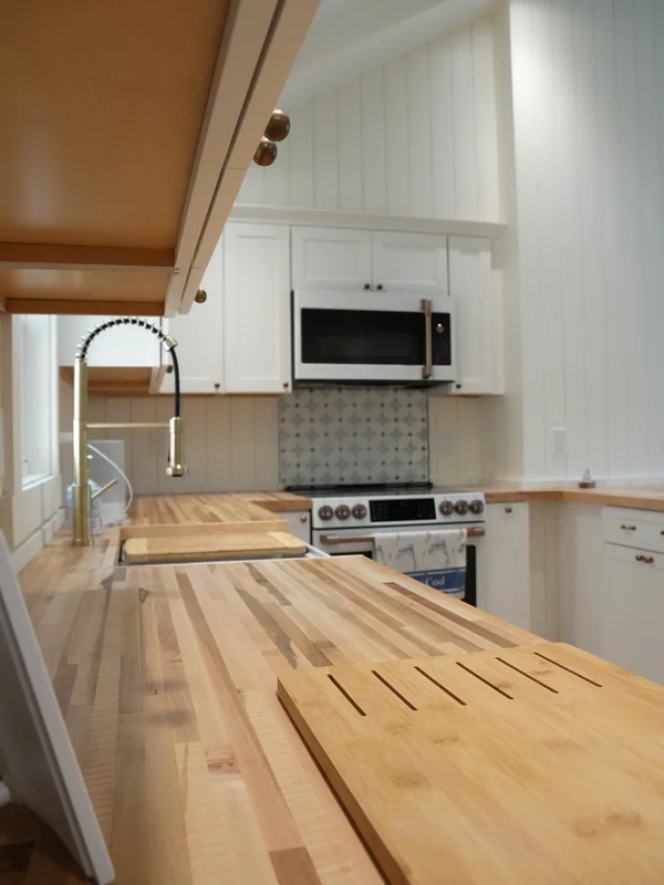 Wood countertop and sink area in a bright white kitchen