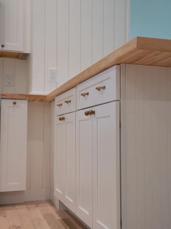 Close-up of white lower cabinets and wood kitchen counter
