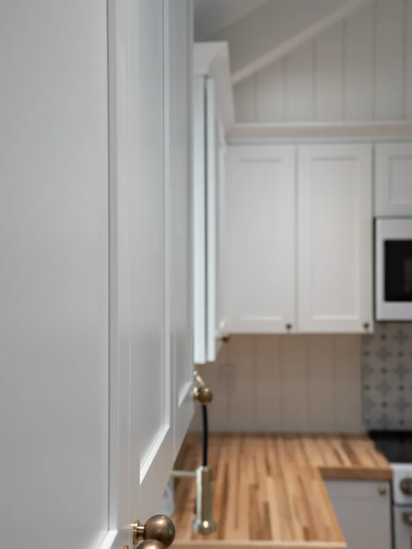 Tall white kitchen cabinetry and wood countertop
