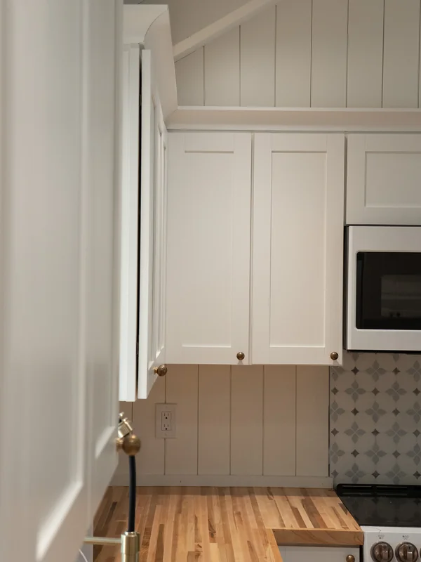 White kitchen cabinets beside a wood countertop and appliance wall