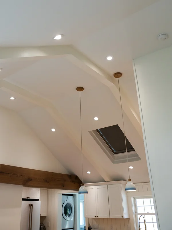 Vaulted kitchen ceiling with recessed lights and wood beam