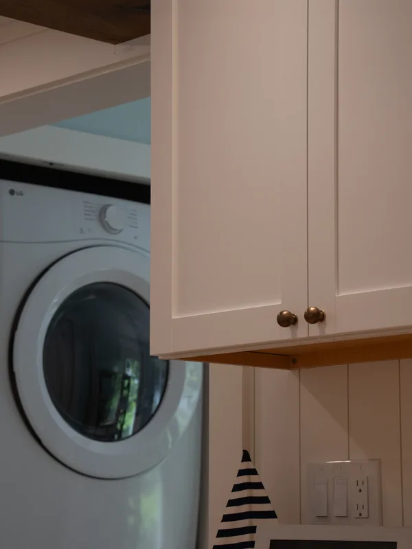 Laundry appliance tucked into white kitchen cabinetry