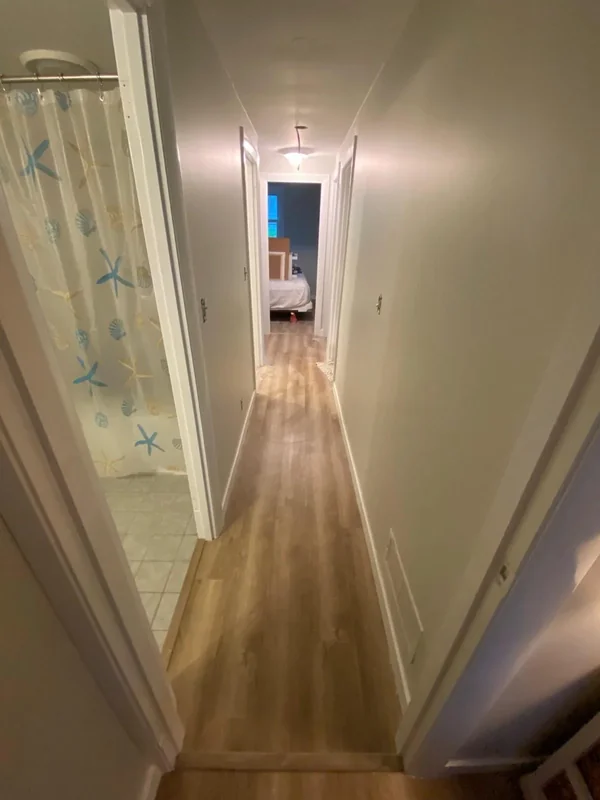 Long interior hallway with fresh wall paint and wood floor
