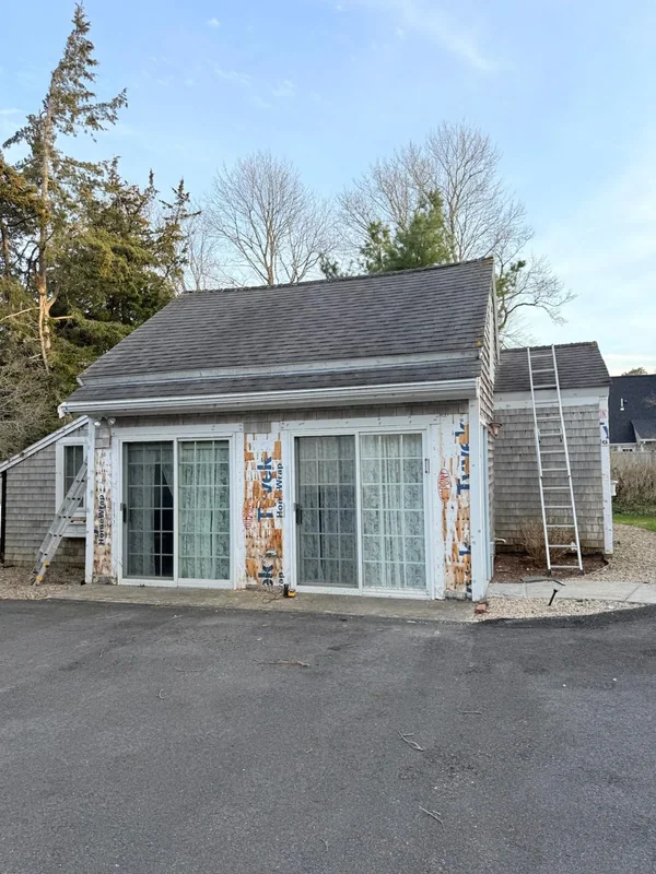 Small finished exterior building with cedar siding and blue doors