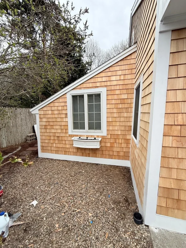 Close side view of cedar shingle siding and white window trim