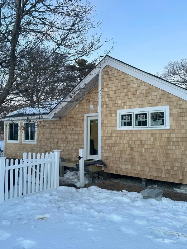 Finished cedar siding exterior behind a white fence