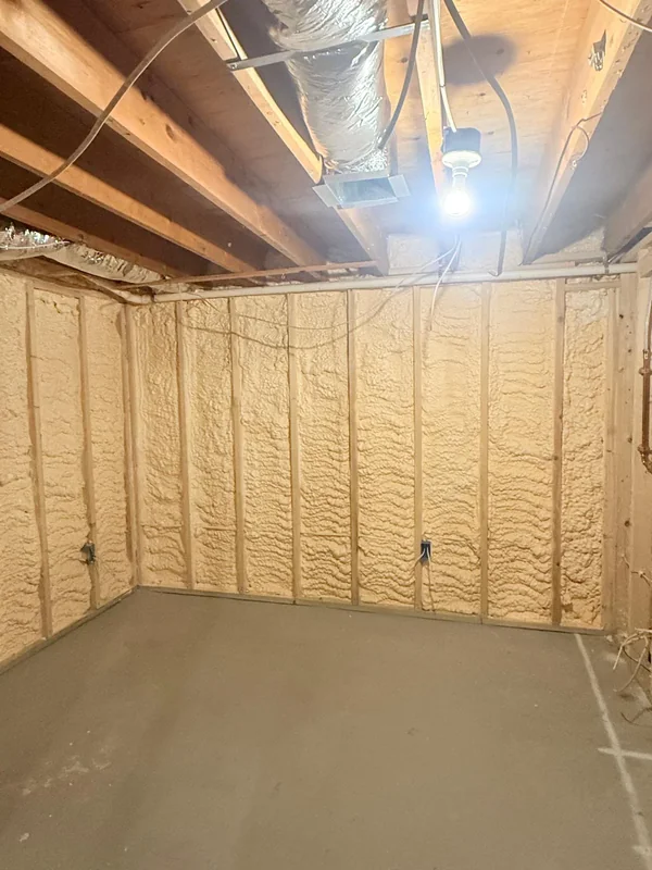 Spray foam insulation across basement wall framing