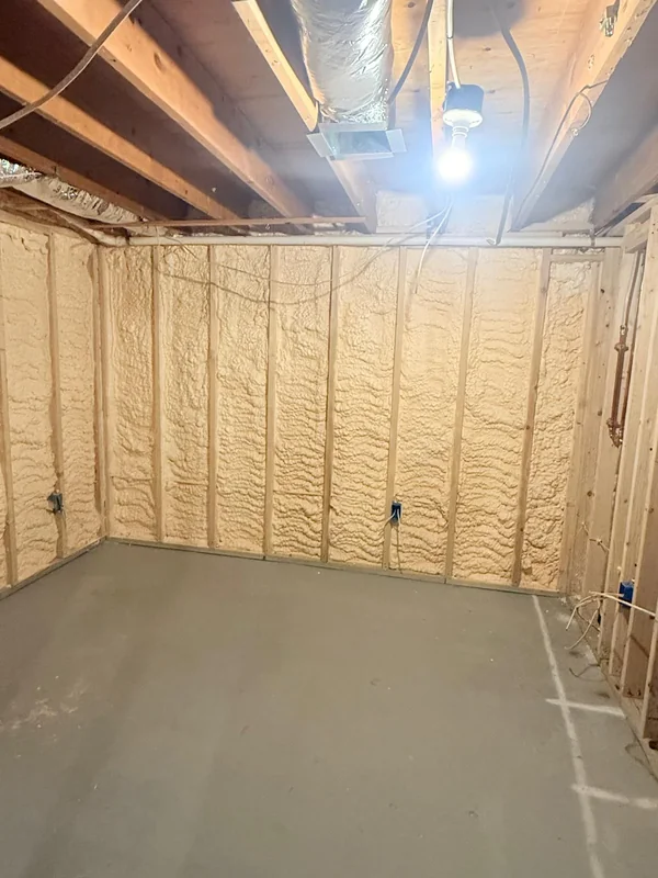 Spray foam insulation on basement walls beneath exposed joists