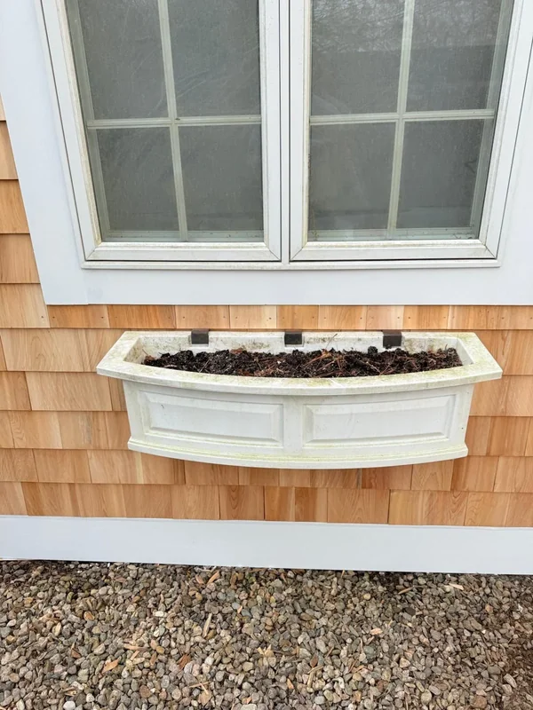 Close-up of a window with a white flower box and trim