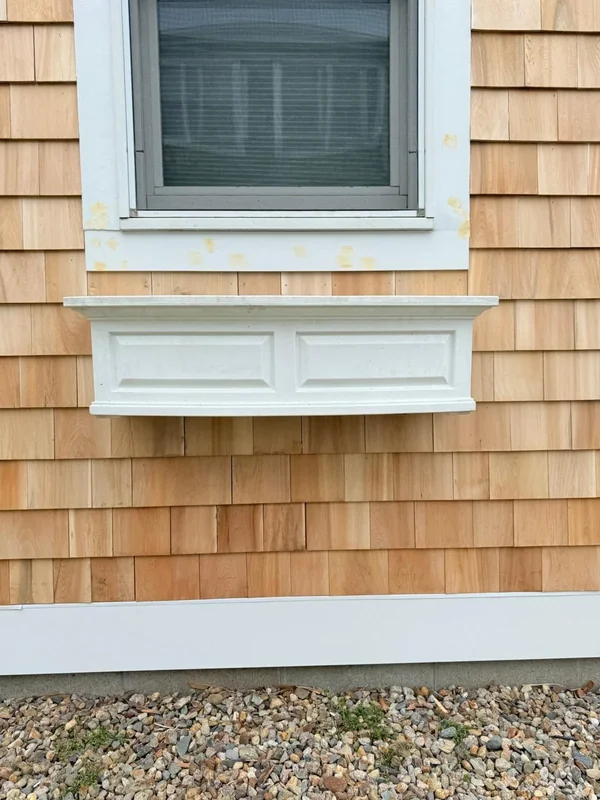 Window with white trim set into cedar shingle siding